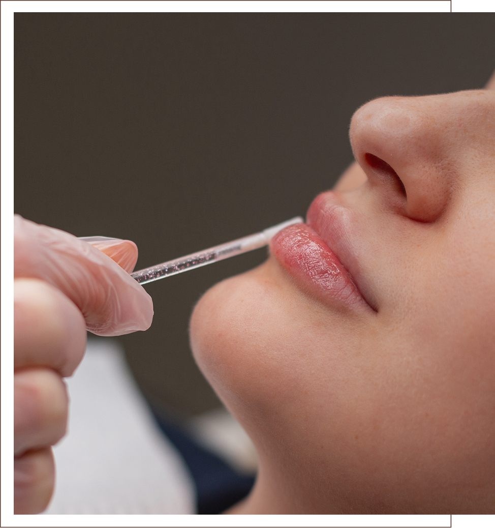 Applying lip gloss with a brush on relaxed lips.