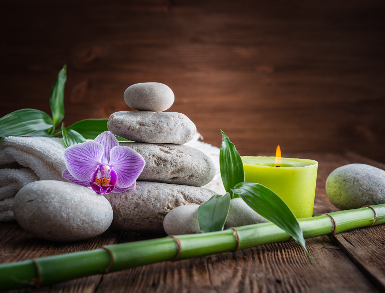 Spa setting with stacked stones, orchid, bamboo, and candle.